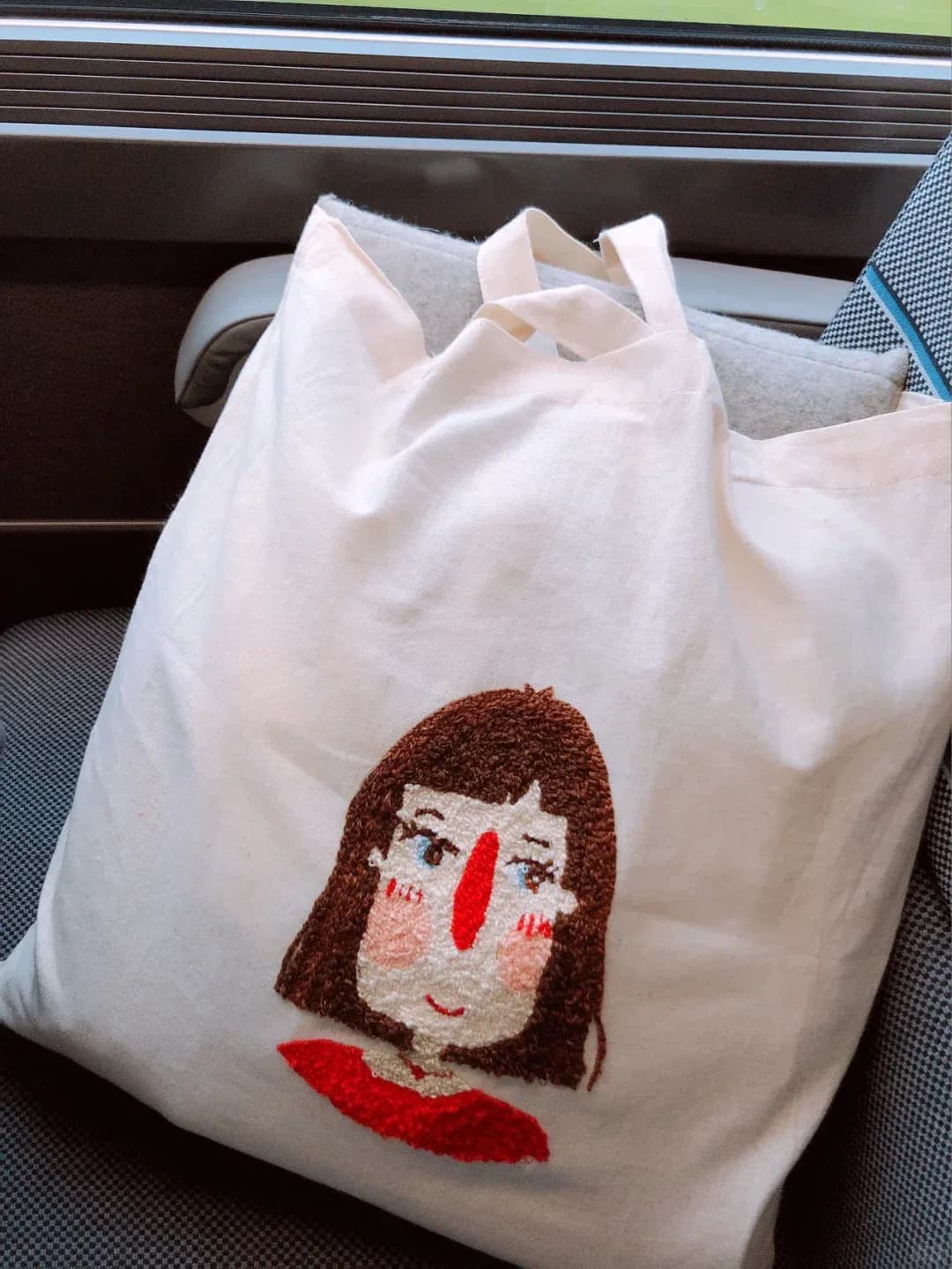 Finished embroidered character tote displayed on a seat