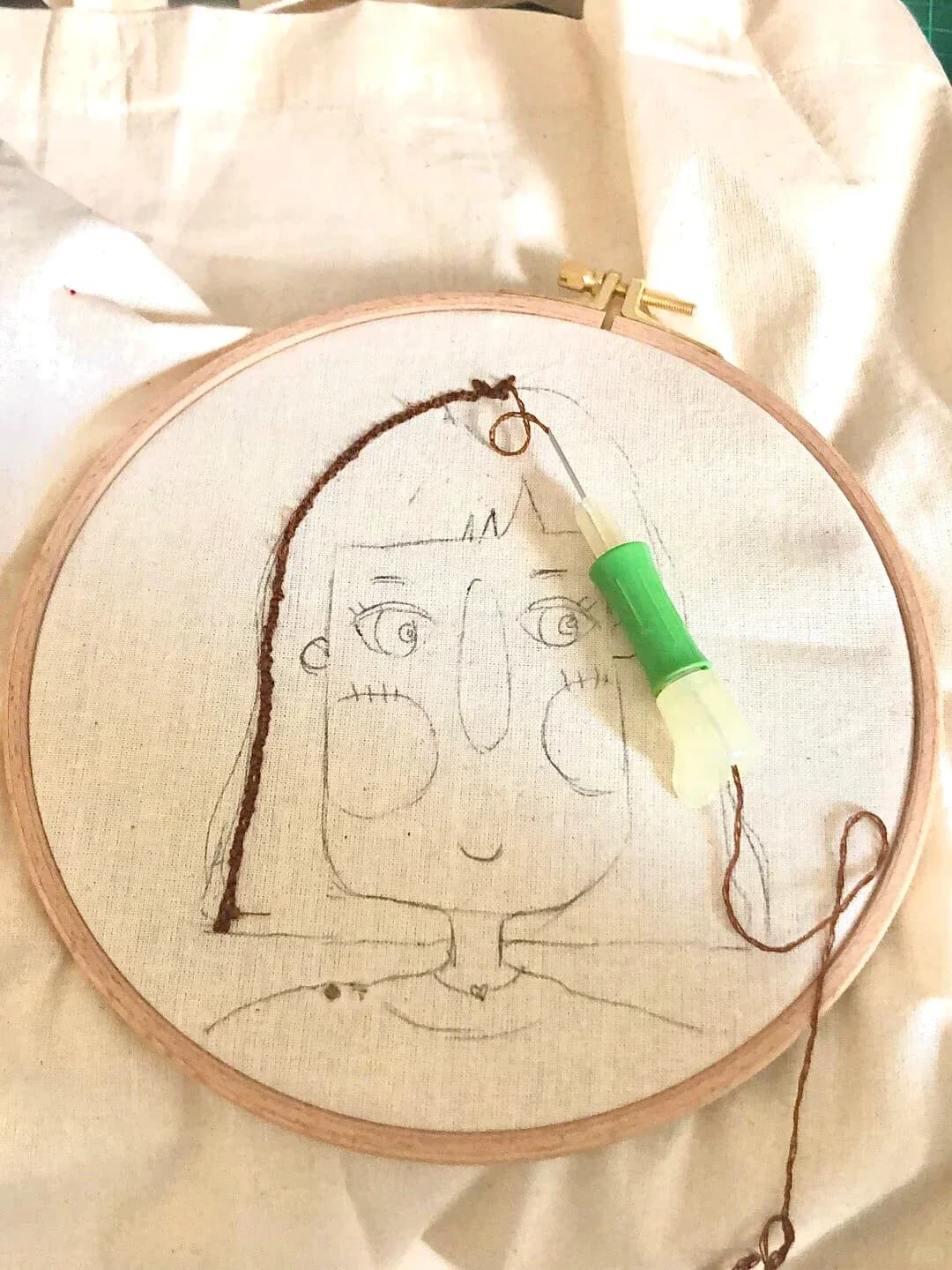 Character drawing and first stitches inside an embroidery hoop