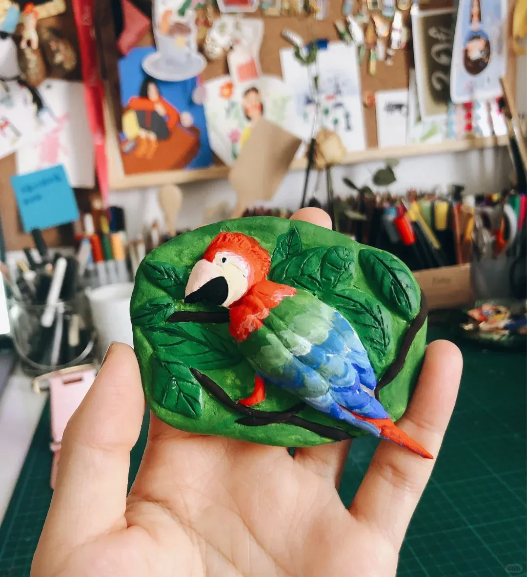 Hand-held parrot clay relief in front of the studio desk