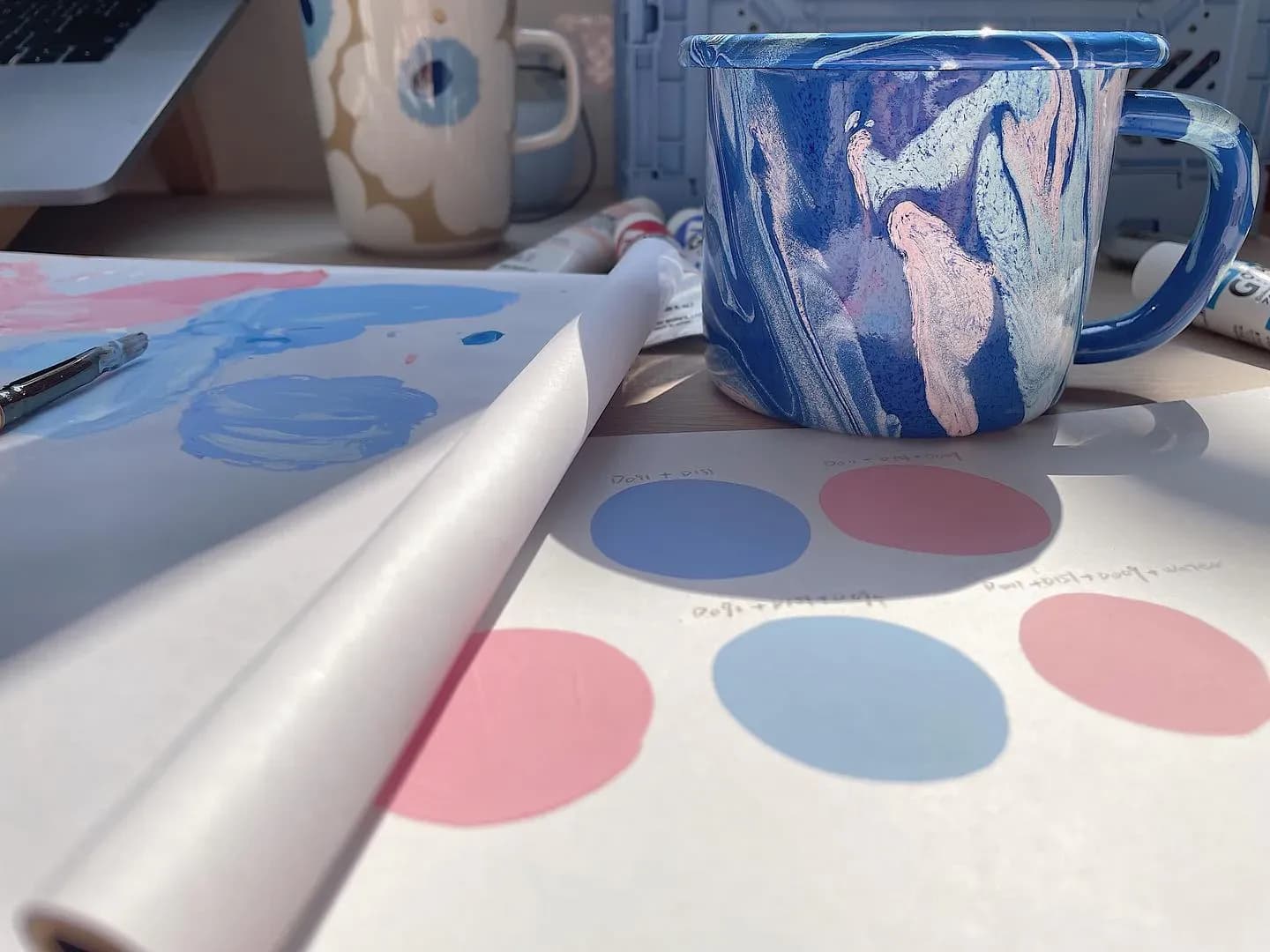 Blue hand-painted cup, illustration studies, and a soft color palette on the worktable