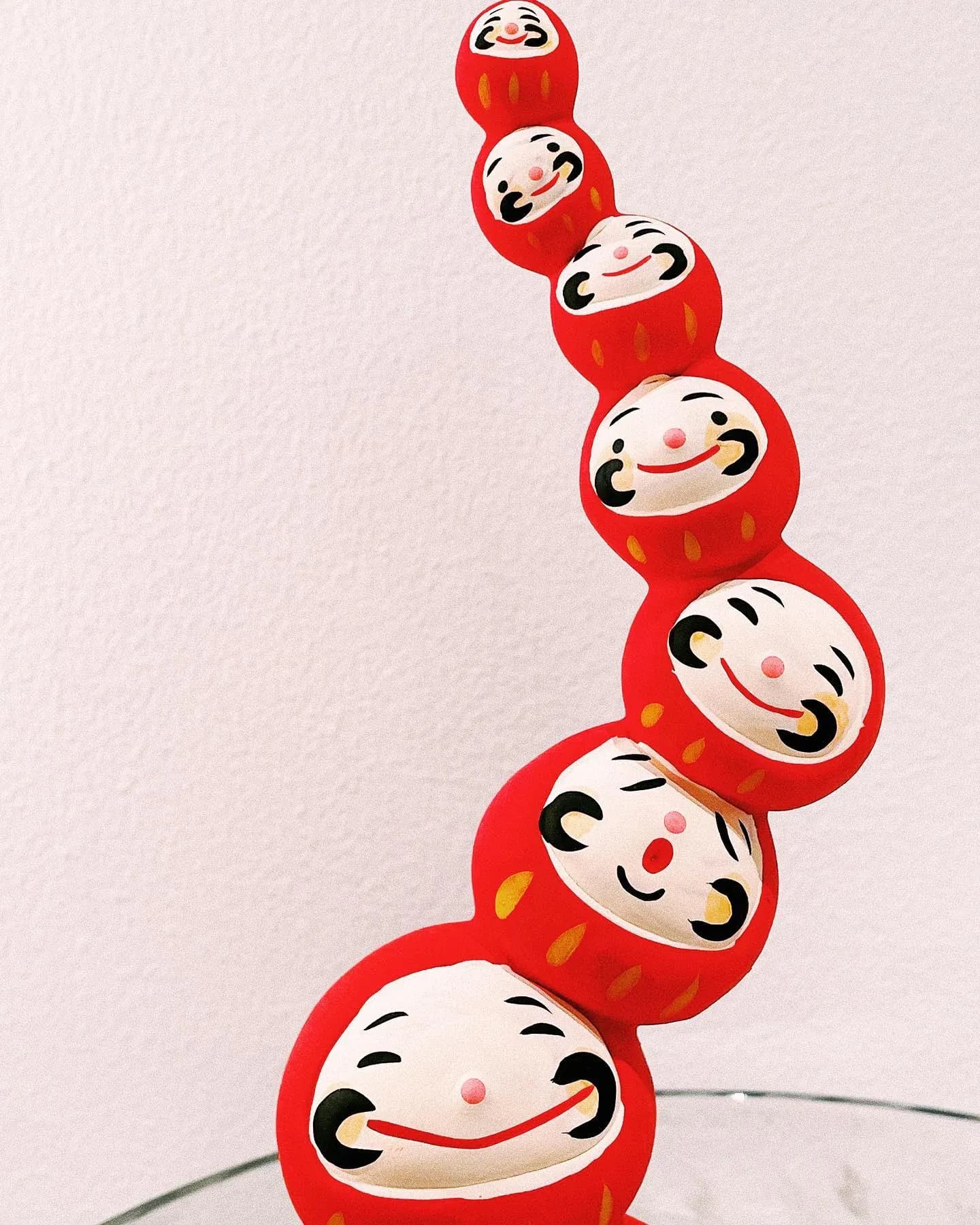 七个红色笑脸达摩角色上下叠放的插画