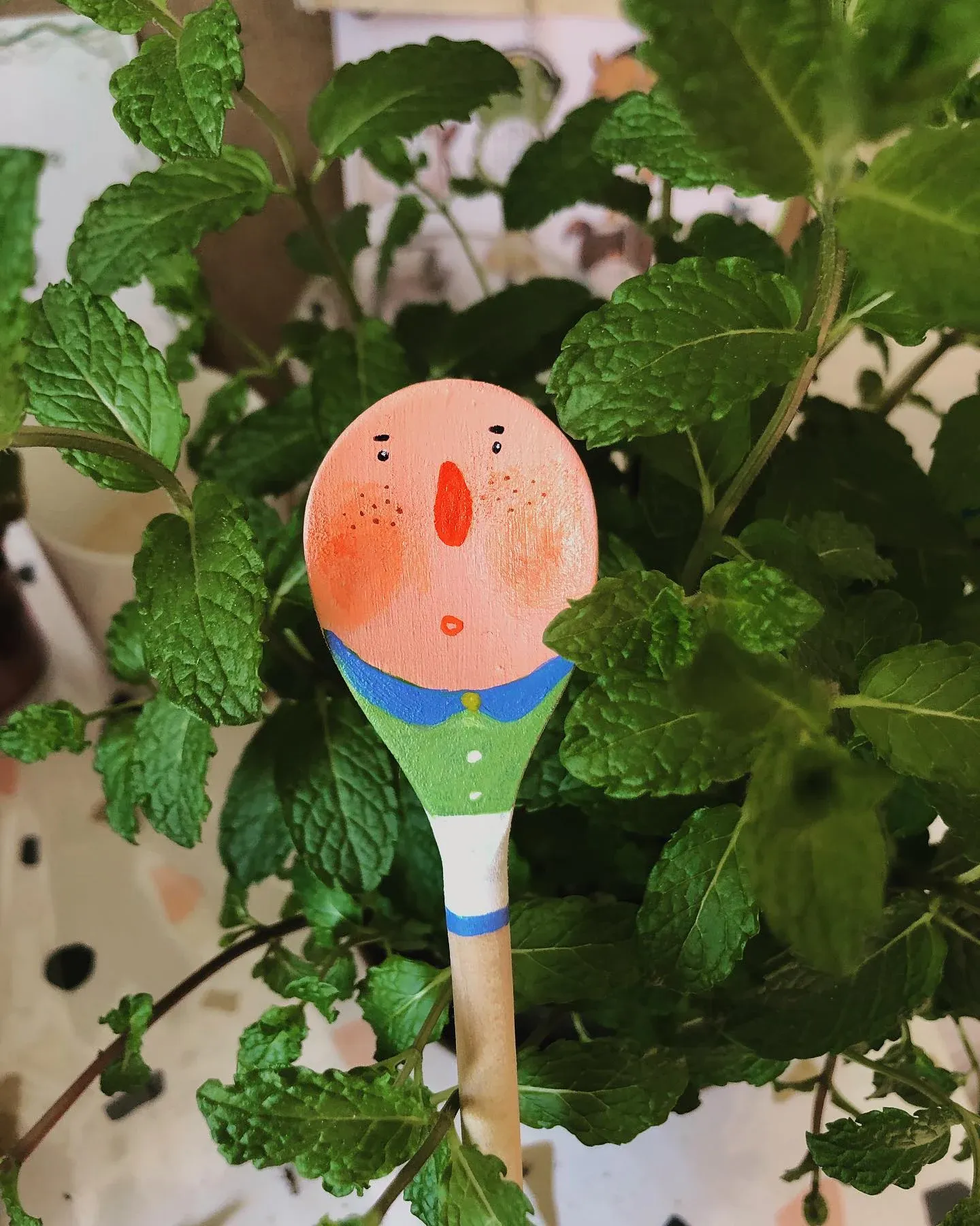 薄荷植物间插着绘有人物头像的手绘木勺